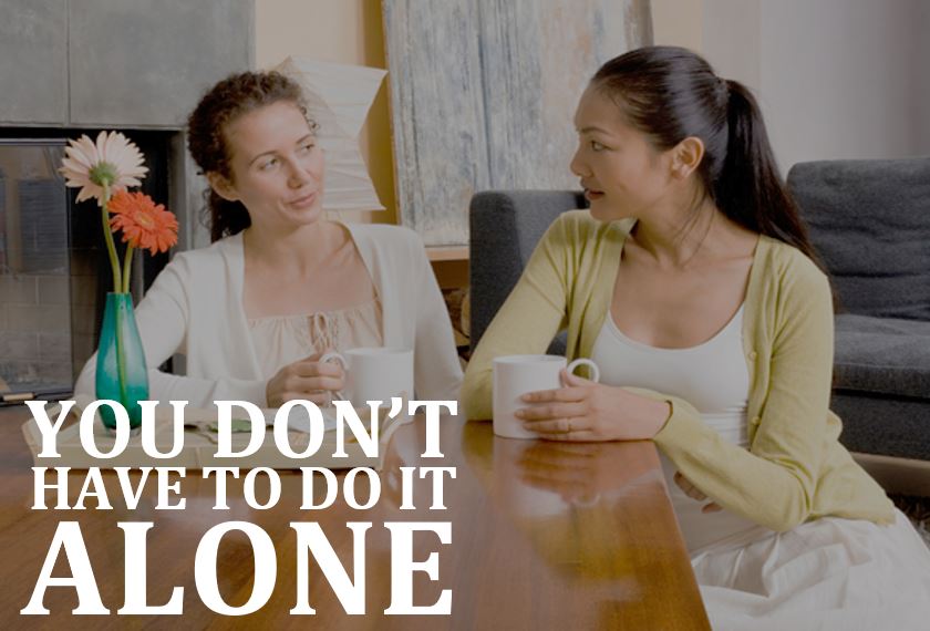 Two women sit at a table with coffee cups, talking. Text reads: You don’t have to do it alone.